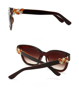 Détail de lunettes de soleil carrées avec accents de strass en forme de feuille brune