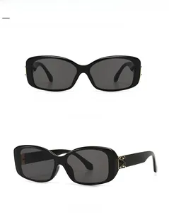Detail view of square frame sunglasses with gold patterned temples and grey lenses