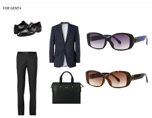 Flat lay of navy striped suit, leather briefcase, monk shoes, and square sunglasses