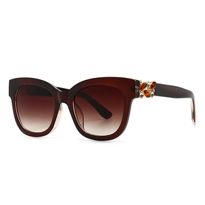 Lunettes de soleil œil de chat marron avec fleurs en strass et verres dégradés sur fond blanc