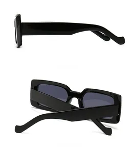 Détail de lunettes de soleil rectangulaires noires avec branches épaisses et design rétro