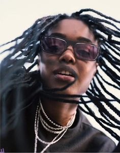 Low angle view of trendy narrow rectangular sunglasses and layered silver necklaces on model