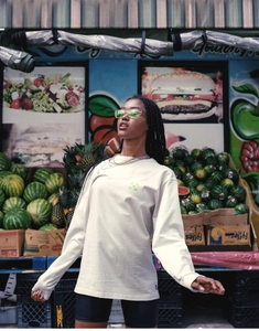 Street style view of a beige oversized long sleeve T-shirt with green RBF print