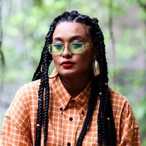 Detail of light green sunglasses and large gold hoop earrings on a trendy model