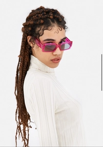 Close-up of a model wearing retro rectangular sunglasses in transparent rose pink and grey