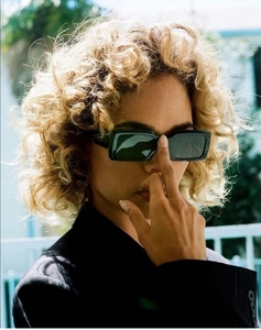 Close-up of black rectangle sunglasses with thick frames and dark lenses on a model