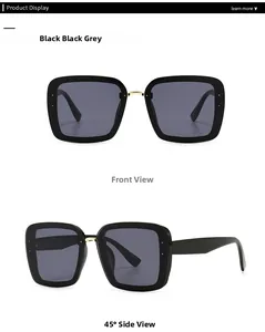 Detail view of large square black sunglasses with gold metal bridge and dark grey lenses