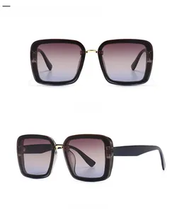 Detail of square oversized sunglasses featuring gradient lenses and gold bridge accents