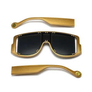 Detailed view of oversized gold frame sunglasses with decorative rivets and dark grey lenses