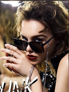 Close-up of black square punk sunglasses with silver rivets and metal chain detail