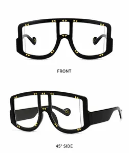 Detail view of wide black frame sunglasses with gold rivets and transparent lenses