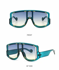 Detail of oversized shield sunglasses in cyan blue with gold rivets and gradient lenses