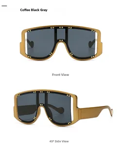 Close-up of oversized gold frame sunglasses with metal rivet studs and dark grey lenses