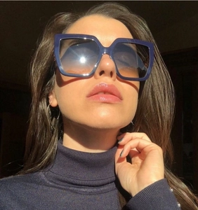 Close-up of navy blue oversized square sunglasses with gradient lenses on a model