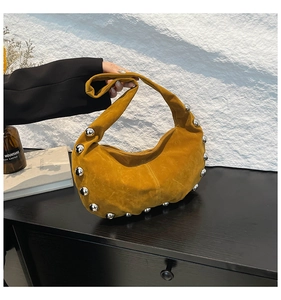 Detail of mustard yellow hobo bag featuring silver rivets and soft suede texture