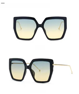 Detail view of large square sunglasses with black frame and blue-yellow gradient lenses