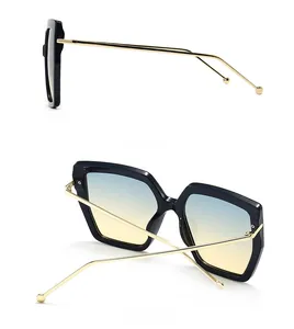 Detail view showing thin gold metal temples and blue-yellow gradient lenses of large sunglasses