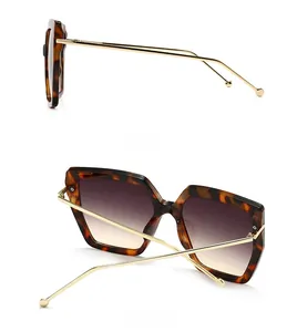 Detail view of tortoiseshell sunglasses with slim gold metal temples and gradient lenses