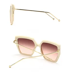 Detail view of cream oversized square sunglasses with gold metal temples and gradient lenses