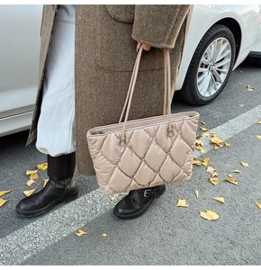 Close-up of beige quilted tote bag with refined texture and zipper for autumn commute