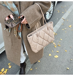 Detail of beige quilted tote bag and leopard print phone case in an autumn outdoor setting