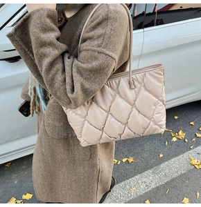 Detail of beige quilted tote bag showing padded texture and slim shoulder straps