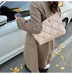 Outdoor shot of beige quilted tote bag showing large diamond pattern and slim straps