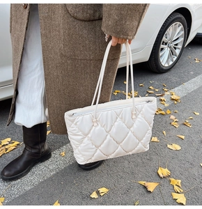 Close-up of white quilted tote bag with large square pattern and zipper closure