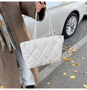 Detailed view of quilted white tote bag with puffy diamond texture and shoulder strap