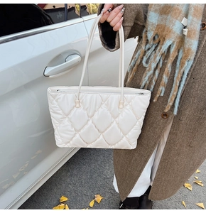 Macro shot of white quilted tote bag with diamond pattern and zipper detail in outdoor setting