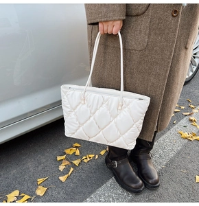 Close-up of white quilted tote bag featuring large diamond stitching and light glossy finish