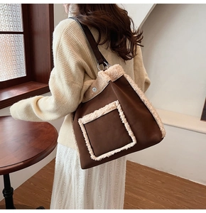 Close-up of brown suede tote bag with white faux shearling trim and leather strap