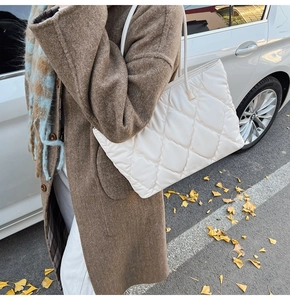 Detailed view of a white quilted tote bag worn with a winter coat and ginkgo leaves