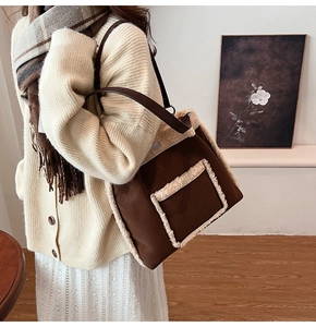 Brown leather tote with white faux fur trim shown worn by a model in a warm setting