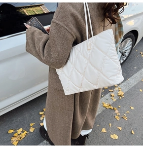 Close-up of a white quilted tote bag featuring a large diamond lattice pattern on the street