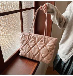 Detail of light pink quilted puffer tote bag with elegant rhombus pattern and glossy finish