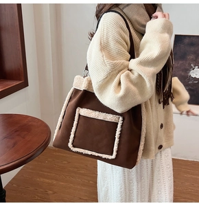 Detailed view of brown suede bucket bag with white faux fur trim and front pocket design