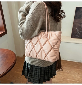 Lifestyle view of a large light pink quilted tote bag worn by a model in a cozy interior