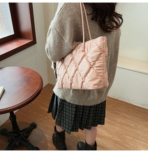 Detail of light pink quilted tote bag with diamond lattice pattern on glossy nylon fabric