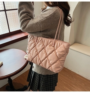 Detail of pink quilted tote bag with slender straps worn over the shoulder by model