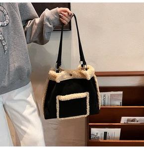 Detail of a large black tote bag featuring cream shearling trim and front pocket contrast