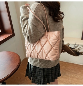 Side view of a light pink quilted tote bag with diamond pattern worn by a model in fall