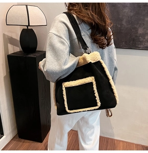 Detail of black suede shoulder bag with plush shearling trim and silver metal hardware