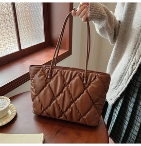 Detailed view of brown quilted tote bag with diamond stitching and glossy finish