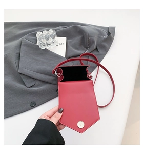 Detail of red crossbody phone bag featuring shield flap and silver magnetic closure