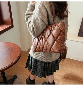 Rear view of brown quilted tote bag showing soft padded texture and elegant drape