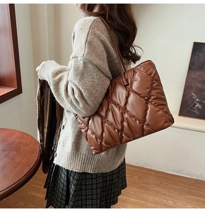 Detail of brown quilted tote bag showing soft puffy texture and sleek shoulder strap