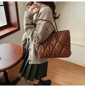Close-up of brown quilted tote bag with glossy finish and elegant shoulder strap