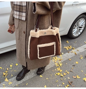 Close-up of brown suede and beige faux shearling tote bag styled with autumn coat