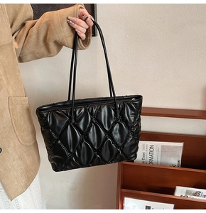 Detail of leaf-shaped quilting on black glossy tote bag with dual shoulder straps
